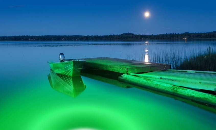 A green underwater LED light near a dock.