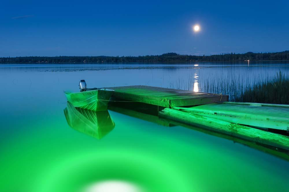 A green underwater LED light near a dock.