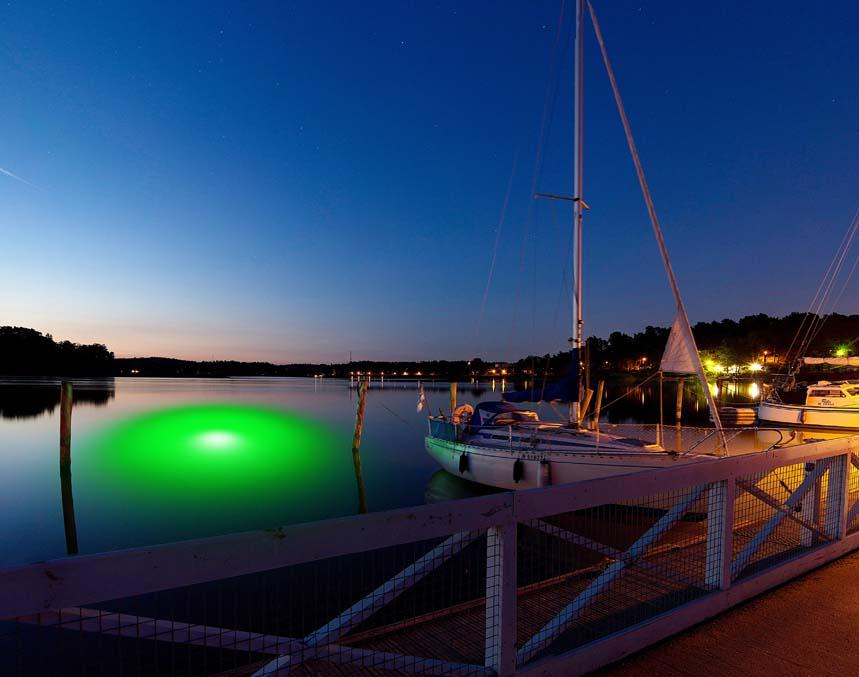 A green colored underwater LED light installed next to a boat.