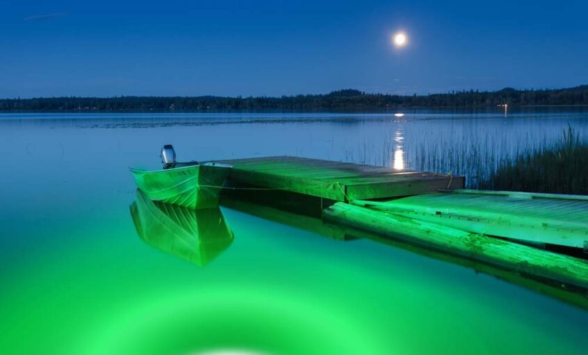 A green colored underwater LED light next to a dock area.