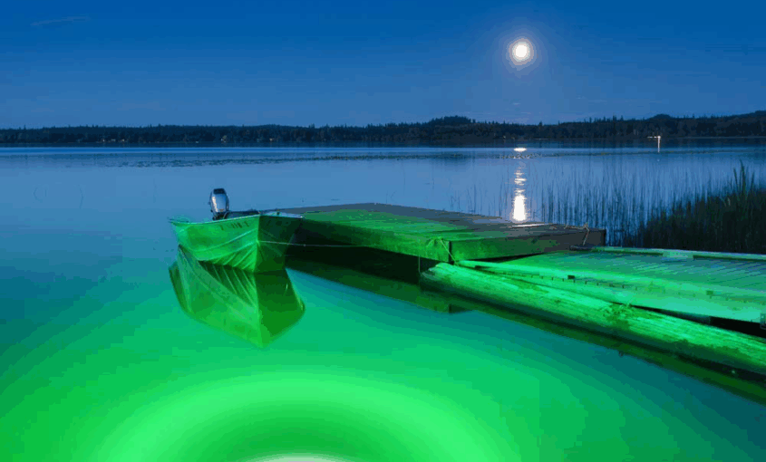 A green colored LED underwater light next to a dock.
