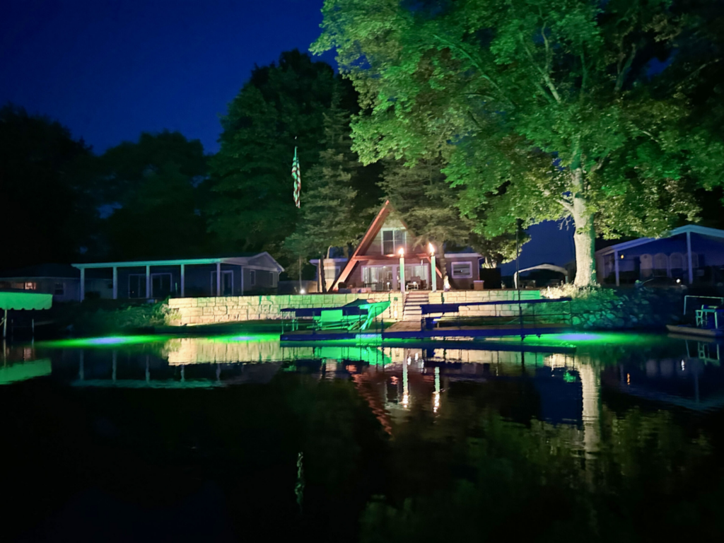 shoreline dock illuminated with green underwater lighting at night