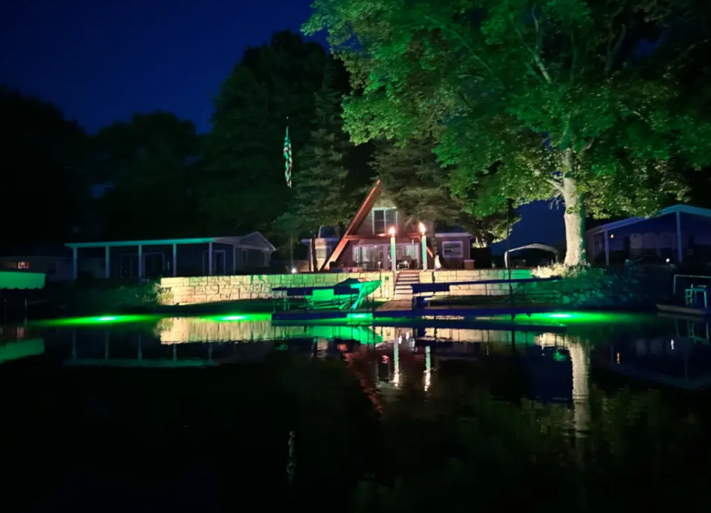 A large property with green underwater lights near the dock. 